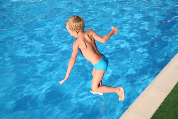 O menino salta na piscina . — Fotografia de Stock
