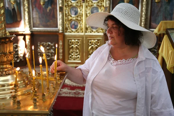 Die Großmutter mit der Kerze in der Kirche. — Stockfoto