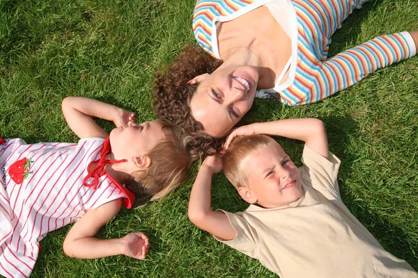 Moeder en kinderen liggen op het gras — Stockfoto