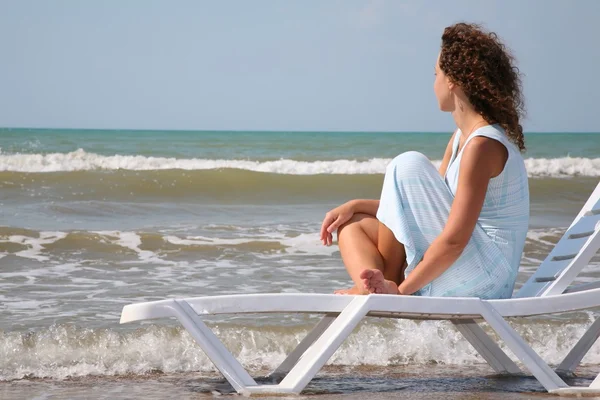 Jovem mulher senta-se no salão de chaise na borda do mar — Fotografia de Stock