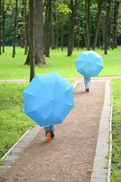 Двое детей под зонтиками в парке — стоковое фото