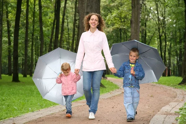 Mãe e crianças sob os guarda-chuvas no parque — Fotografia de Stock