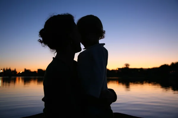 La silueta de la madre con el niño sobre el fondo del sol — Foto de Stock