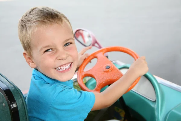 Мальчик в игрушечной машине — стоковое фото