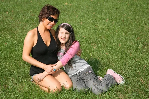 Mãe com adolescente na grama sentar — Fotografia de Stock