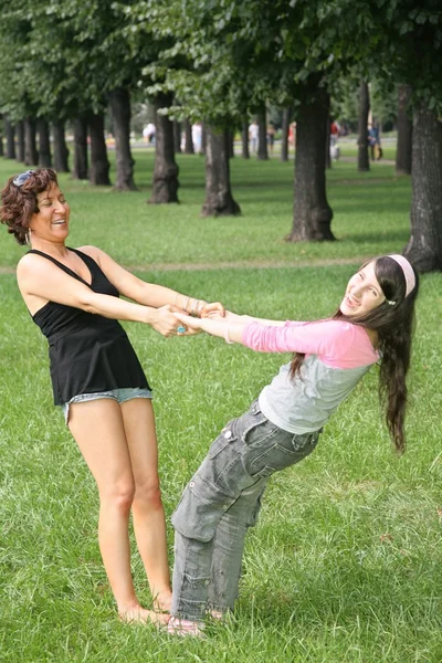 母と娘公園の芝生の上に立つ — ストック写真