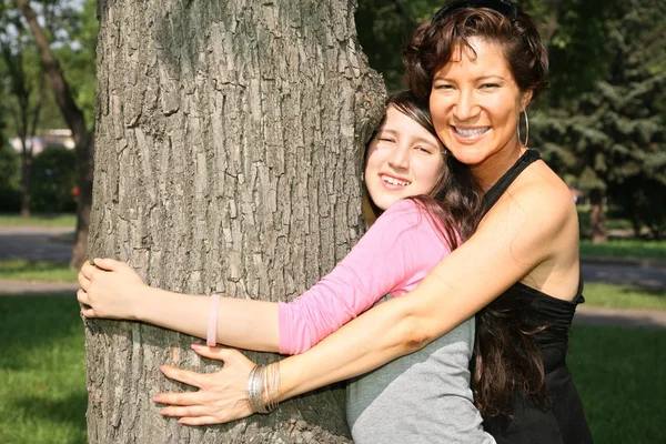 Madre e hija abrazan el árbol —  Fotos de Stock