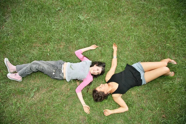 母亲和女儿少年谎言在草地上 — 图库照片