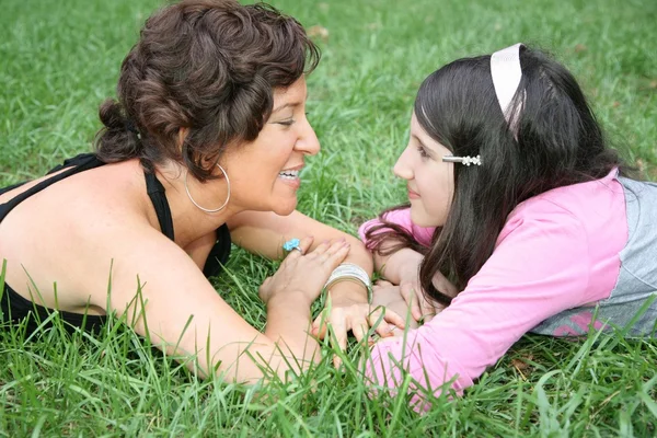 Mother and daughter lie on the grass and look at each other — Stock Photo, Image