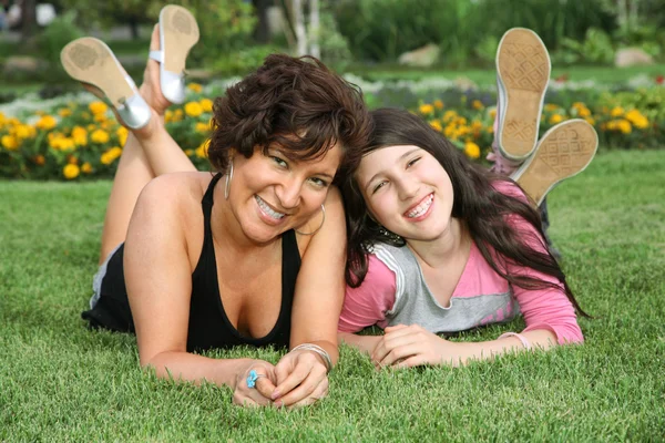 Mother and daughter lie on the grass and smile — Stock Photo, Image