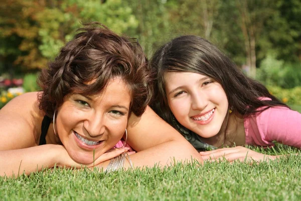 Moeder en dochter glimlach 2 liggen op het gras — Stockfoto
