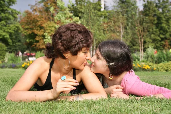 Mother and daughter lie on the grass and look at each other — Stock Photo, Image