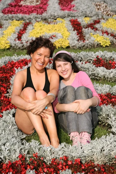Anne ve kızı çiçekler arasında oturmak — Stok fotoğraf