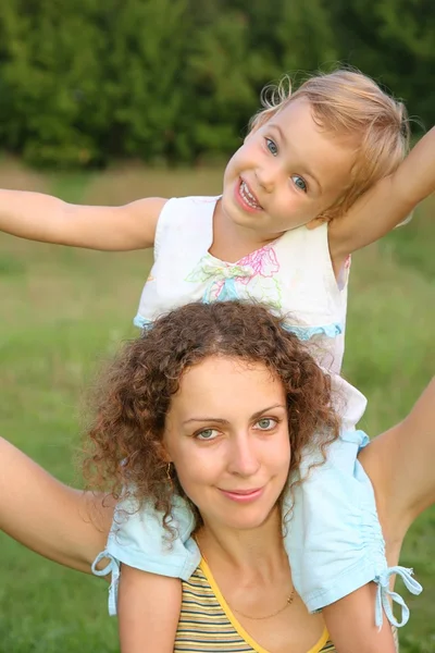 Daughter sits on the shoulders in mother — Stock Photo, Image
