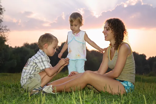 Мама з дітьми сидить на траві — стокове фото