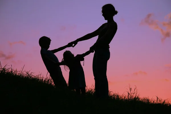 Mother and children are held for the hands on the sunset — Stock Photo, Image