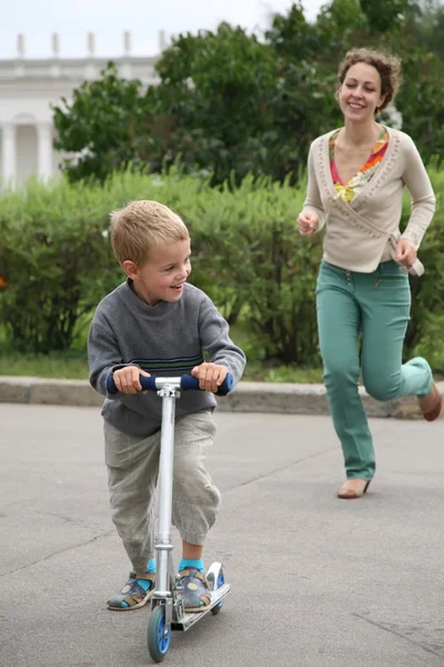 Mãe corre atrás do filho na bicicleta — Fotografia de Stock