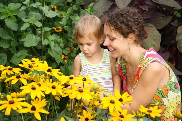 Madre e hija miran flores —  Fotos de Stock