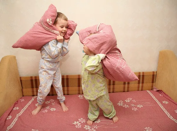 Дети играют с подушками на кровати — стоковое фото