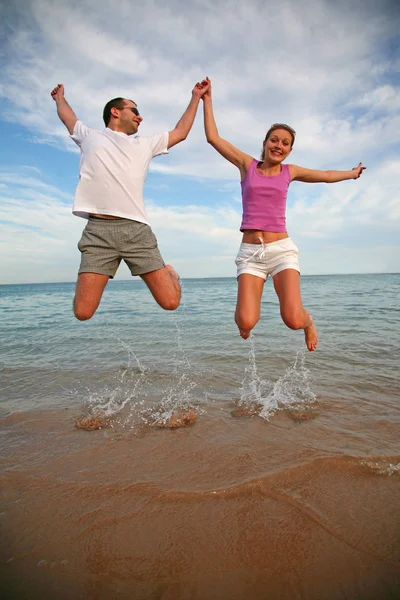 Man and woman jump above the sea — Stock Photo, Image