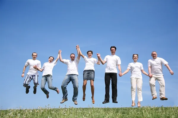 Group of friends in white T-shorts jump together — Stock Photo, Image