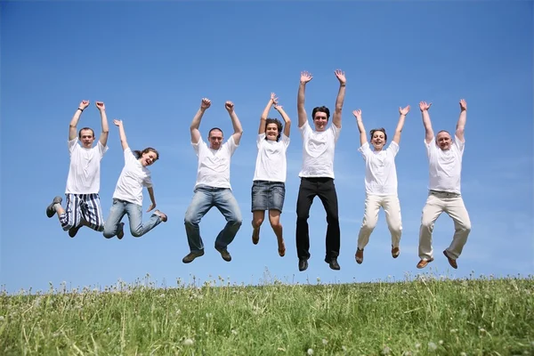 Seven friends in white T-shorts jump together — Stock Photo, Image