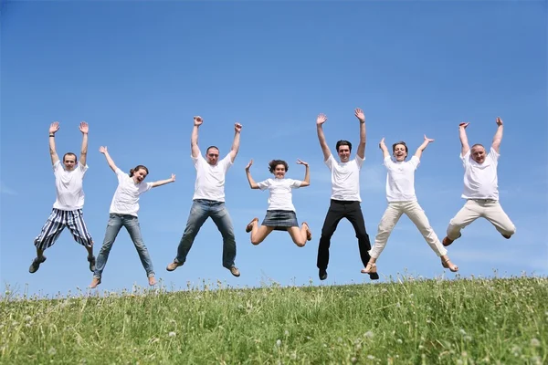 Seven friends in white T-shorts joyfully jump together — Stock Photo, Image