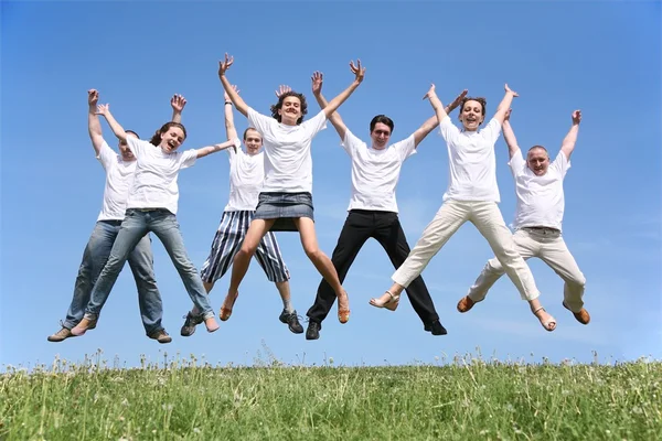 Sept amis en T-short blanc balancent les mains dans un saut — Photo