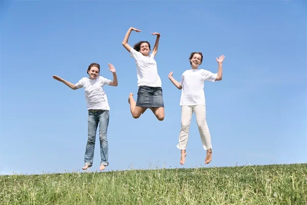 Three girlfriends in white T-shorts jump together — Stock Photo, Image