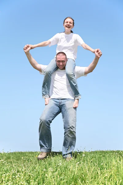 Girl on boy's shoulders on grass — Stock Photo, Image