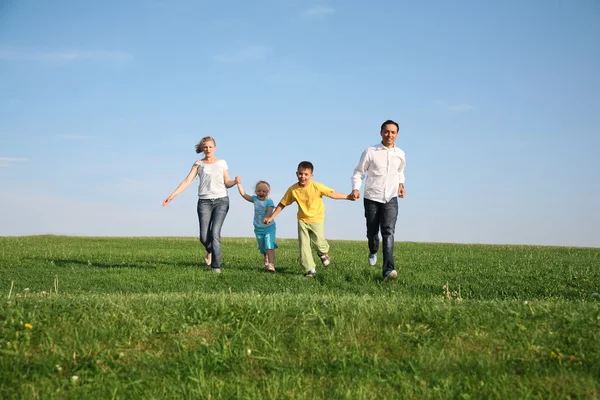 Family of four running grass sky — Stock Photo, Image