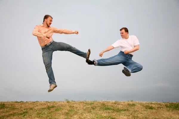 Two men kicking in jump — Stock Photo, Image