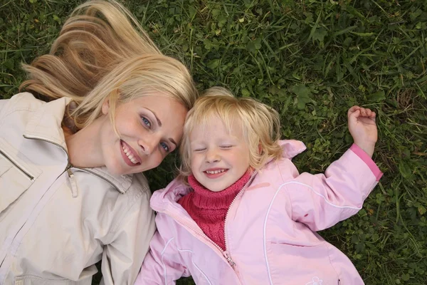 Mother and daughter lie on the grass and look upward — Stock Photo, Image