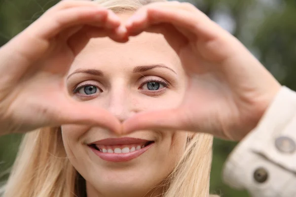 Vrouw toont het hart als handen — Stockfoto