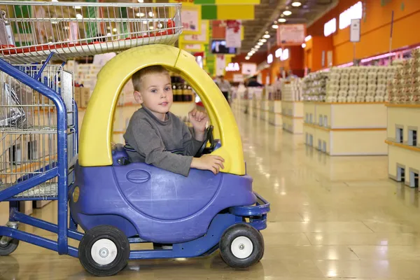 Ребенок в игрушечном автомобиле в супермаркете — стоковое фото