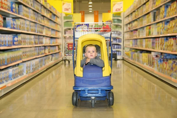 Мальчик в игрушечном автомобиле в супермаркете — стоковое фото