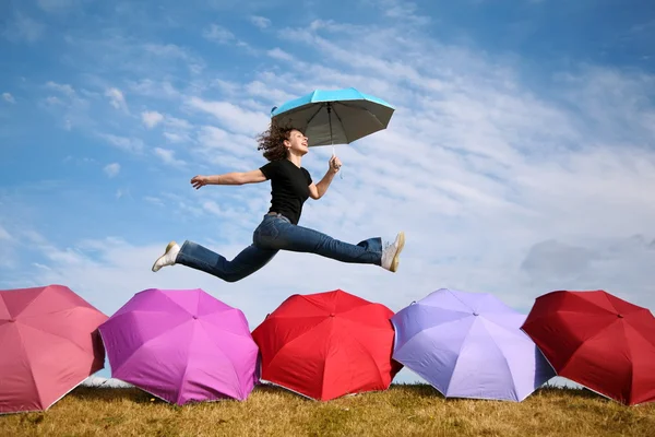 Молодая женщина прыгает с зонтиком над зонтиками — стоковое фото