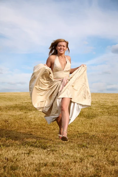 Kobieta w sukience biegnie wzdłuż łąki — Zdjęcie stockowe