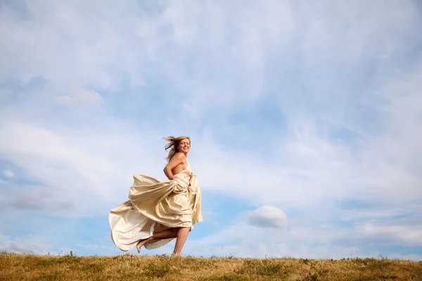 Giovane donna in abito corre lungo il prato — Foto Stock