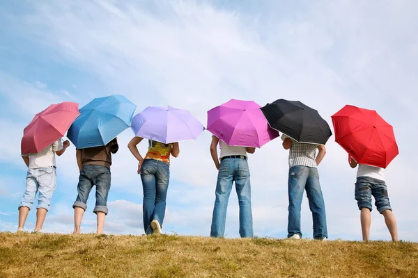 Ayakları üstünde-e doğru çayır arka tarafından şemsiyelerle grubu — Stok fotoğraf