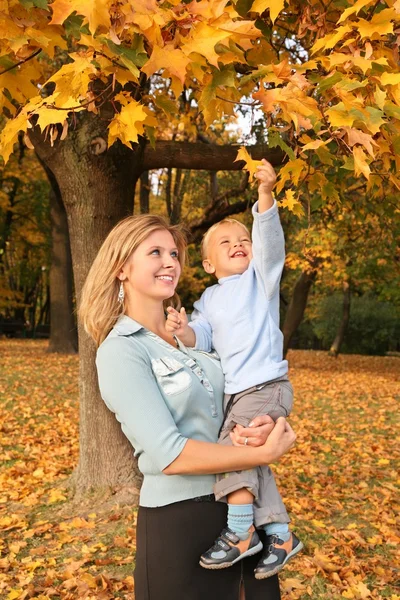 Blauwogige blond met de zoon in het park in het najaar — Stockfoto