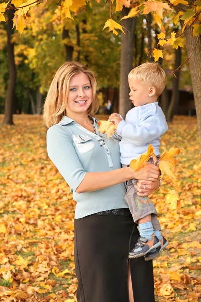 Szőke kék szemű őszi parkban fiával — Stock Fotó