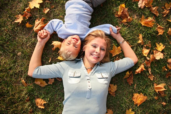 Mère avec enfant repose sur l'herbe d'automne — Photo