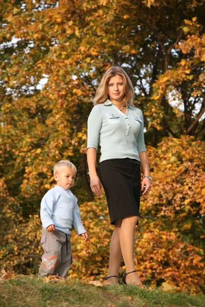 Loira de olhos azuis vai para um passeio com o filho no parque no outono — Fotografia de Stock