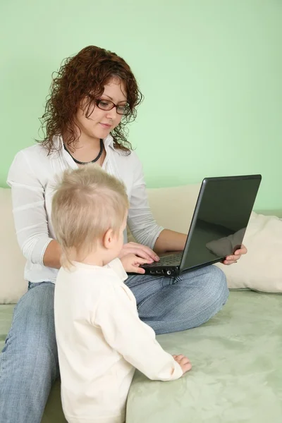 Молодая женщина в очках с ноутбуком и ребенком — стоковое фото
