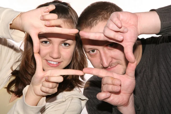 Homem e mulher olham através de uma moldura feita por suas mãos — Fotografia de Stock