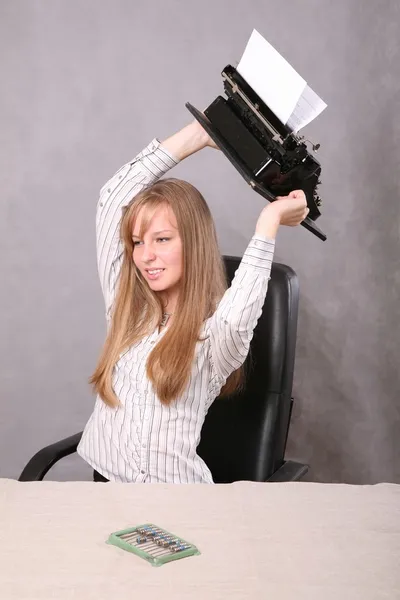 Девушка в раздражении бросает пишущую машинку — стоковое фото