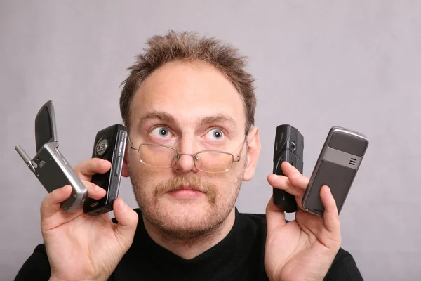 Человек с бородой и четырьмя телефонами — стоковое фото