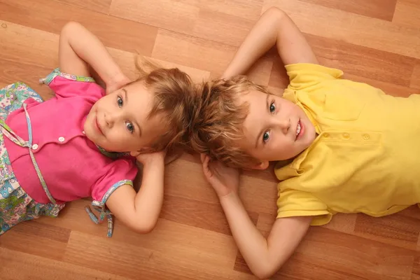 Bruder und Schwester liegen am Boden — Stockfoto