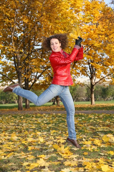 Menina no casaco vermelho salta no parque no outono — Fotografia de Stock